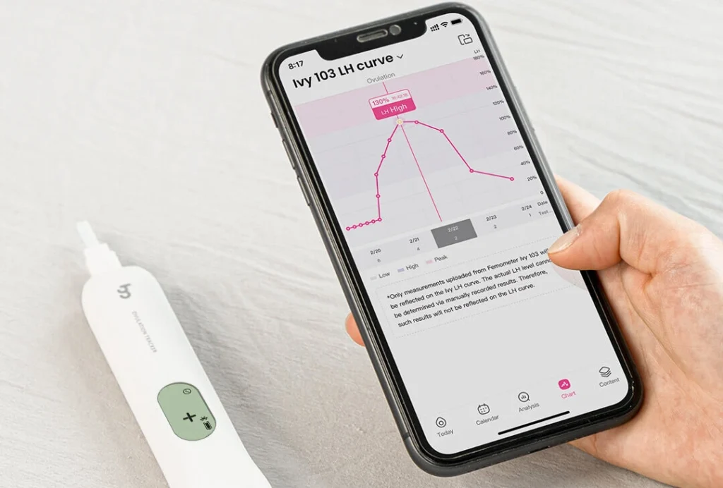 Woman seated at a bright window, holding an OPK test calmly, looking at her phone with a fertility app open โ capable, unhurried, in control