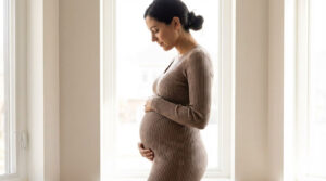 pregnant woman in profile view showing a visible baby bump at around 20 weeks gestation