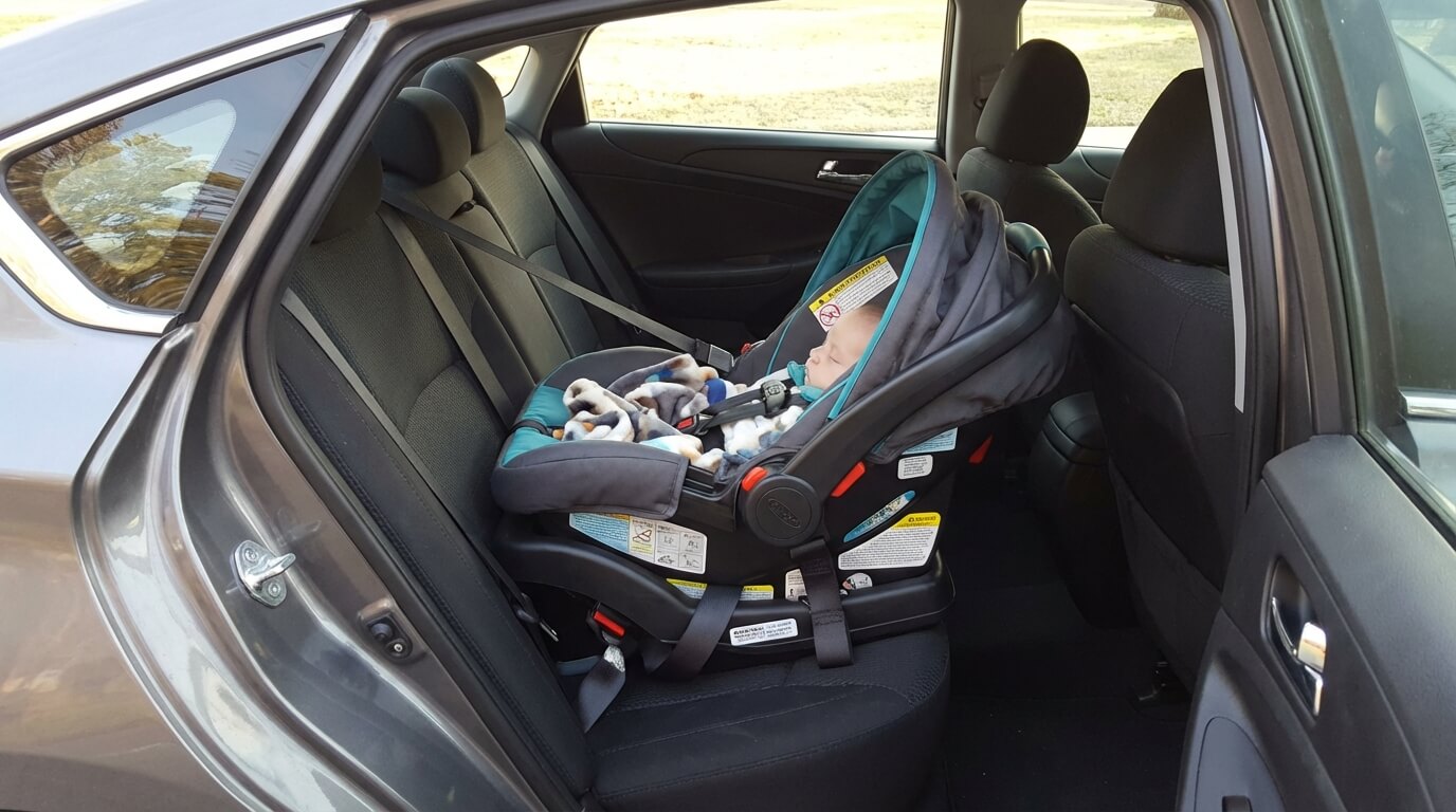 rear-facing infant car seat properly installed in the back seat of a sedan